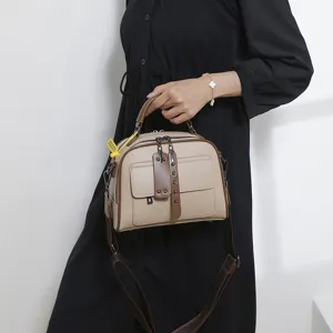 Nahaufnahme der beige Leder Umhängetasche mit braunem Griff und Vordertaschen-Design.