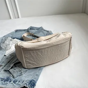 Detailaufnahme der beigen Nylon Umhaengetasche mit weicher Textur und grossem Volumen.