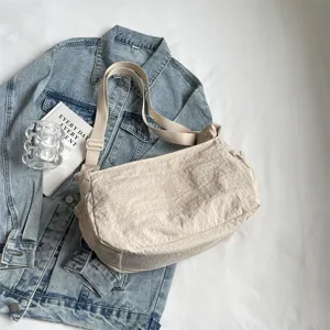 Nahaufnahme einer lässigen, hellen Nylon-Umhängetasche auf einer blauen Jeansjacke.