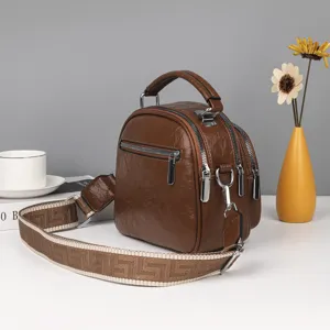 Braune weiche Leder-Mehrschicht-Umhängetasche mit breitem gemusterten Gurt für Damen.
