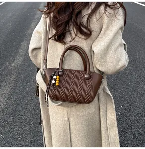 Detailaufnahme der braunen Vintage-Stepp-Umhängetasche mit Perlenanhänger und Tragegriff.