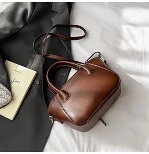 Detailansicht einer vintage braunen Handtasche mit Henkel und einem eleganten Blazer.