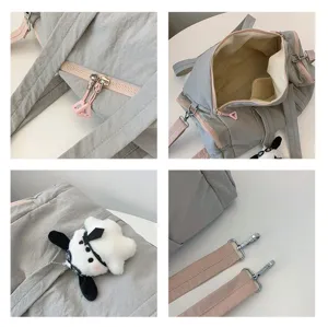 Nahaufnahme der Details mit Reißverschluss, Innenfach, Plüschhund-Anhänger und Metallriemen.