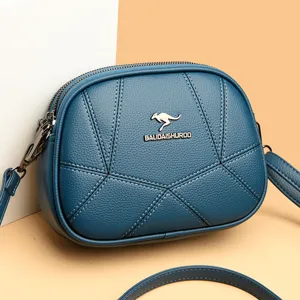Blaues Umhaengetasche aus Leder mit dekorativen Naehten und stilvollem Metalllogo.