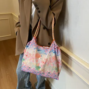 Nahaufnahme einer bunten Tragetasche mit Blumen-Ölgemälde-Druck und Kordelzug-Trägern.