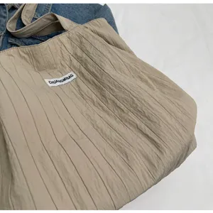 Detailansicht der beigen plissierten Canvas Tasche, die weiche Textur und Stoffqualität zeigt.
