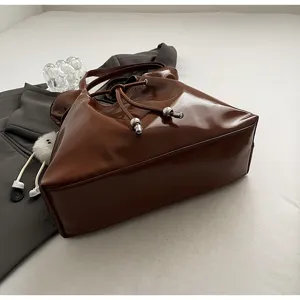 Glänzende braune Beuteltasche Nahaufnahme, glatte PU-Ledertextur, Kordelzugverschluss, schick.