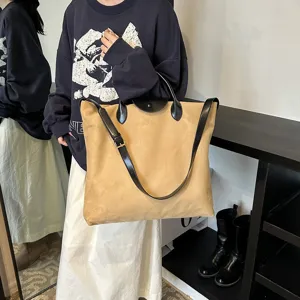 Detailaufnahme der beigen Wildleder-Tasche mit schwarzen Ledergriffen und verstellbarem Gurt.