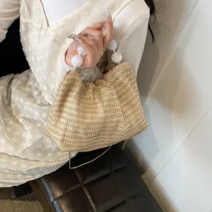 Detailansicht der Damen Strohhandtasche mit weißem Perlenhenkel und sommerlicher Textur.