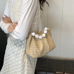 Detailansicht der lässigen Sommer Strohtasche mit elegantem Perlenhenkel und Kette.