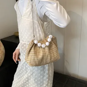 Detailaufnahme der Stroh-Umhängetasche mit weißer Perlen-Kette und lässigem Design