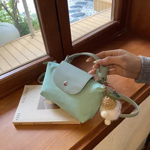 Detailansicht der mintgrünen Nylon Mini-Knödeltasche mit Tragegriff und flauschigem Anhänger.