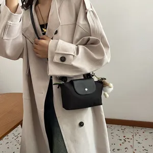 Detailansicht der schwarzen Nylon Umhängetasche im Dumpling-Stil mit Plüschanhänger.