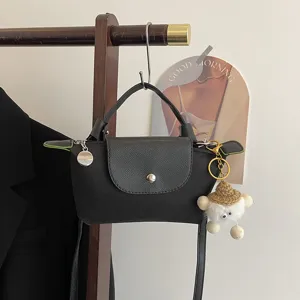 Nahaufnahme einer kleinen schwarzen Nylon-Umhängetasche mit Lederklappe und Druckknopfdetail.