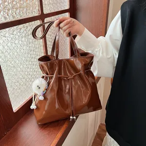 Braune Lackleder Umhängetasche für Damen mit stylischem Kordelzug und süßem Plüschanhänger.