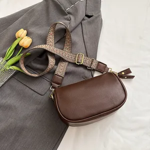 Detailansicht einer vintage braunen Leder Umhängetasche mit einem breiten Ethno-Gurt.