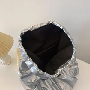 Silberner metallischer Kordelzug Rucksack Detail zeigt glänzenden Stoff und schwarzes Innenfutter.