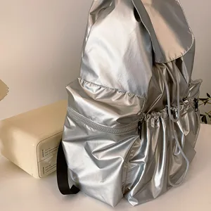 Nahaufnahme Detail des silbernen metallisch glänzenden Rucksacks mit Fronttasche und Kordel.