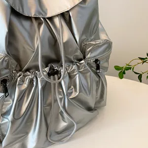 Detailansicht des metallisch glänzenden Kordelzug-Rucksacks mit Textur und Reißverschluss.