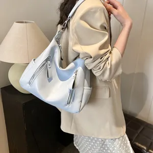 Hellblaue slouchy Schultertasche Detailansicht mit weicher Textur und praktischen Reißverschlüssen.