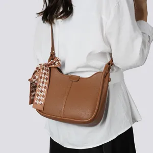 Detailansicht der stilvollen braunen Lederschultertasche mit einem schicken Karoschal.