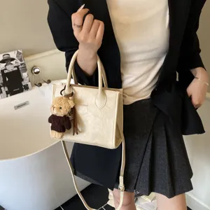 Schicke beige Umhängetasche für Damen mit süßem Bären-Plüschanhänger, trendiges Design.