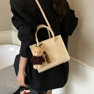 Detailansicht der minimalistischen Beigetasche mit süßem Teddybär-Anhänger und praktischem Gurt.