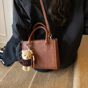 Nahaufnahme der braunen Lederhandtasche mit niedlichem Plüschbären-Schlüsselanhänger, tolles Design.