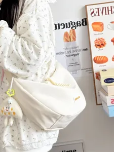 Weisse Canvas Dumpling Umhaengetasche Detailansicht mit weichem Stoff und niedlichem Anhaenger.