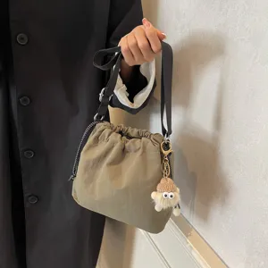Lässiger Nylon-Beutel-Umhängetasche mit Kordelzugverschluss und niedlichem Plüsch-Anhänger.