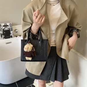 Elegante schwarze Handtasche aus Leder mit niedlichem Bärenanhänger, modische Tasche.