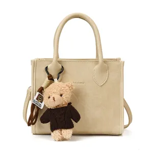 Minimalistische beige Eimer Tasche mit süßem Teddybär Anhänger, stilvolle Leder Umhängetasche.