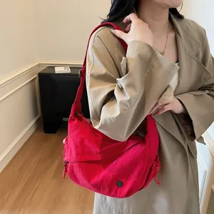 Nahaufnahme einer roten Umhängetasche aus Nylon, getragen von einem Model im lässigen Stil.