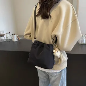Detailansicht der lässigen Nylon-Eimer-Umhängetasche, schwarze Crossover-Tasche mit Anhänger.