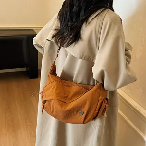 Detailansicht einer braunen Freizeittasche aus Nylon als Umhängetasche am Model getragen.