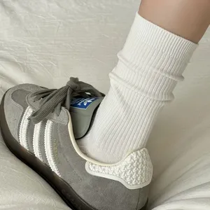 Primo piano dettagliato di calzini medi a coste bianchi da donna abbinati a sneakers casual.