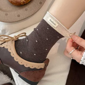 Gros plan détaillé de chaussettes rétro à pois avec des revers côtelés contrastés et une étiquette.