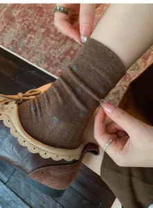 Primo piano dettagliato di calze al polpaccio in cotone marrone retrò con fiori abbinate a scarpe.