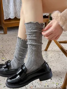 Primo piano di calzini slouch in maglia grigia con bordo in pizzo, motivo traforato e stile.