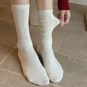 Detailed close-up of vintage hollow-out knit mid-calf women socks in white, stretchy fit.