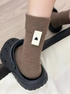 Vista dettagliata di calzini slouch in maglia a costine marroni con etichetta a cuore.