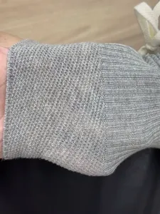 Vista dettagliata delle calze lavorate a maglia grigia con trama a coste e cordoncino.