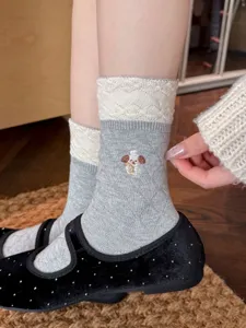Gros plan détail de chaussettes pour femmes grises avec broderie chiot et revers en dentelle.
