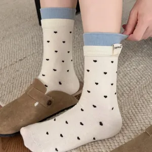 Nahaufnahme der süßen koreanischen Herz-Mustersocken mit blauen gerippten Bündchen im Detail.