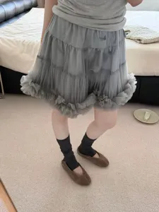 Detailed view of women's stylish grey stirrup socks and tutu skirt outfit for spring.