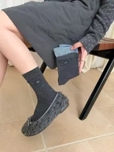 Primo piano dettagliato dei calzini medi a righe autunnali da donna con un design grigio e blu.