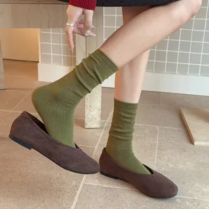 Retro green ribbed mid-calf socks paired with stylish brown suede flat shoes for women.