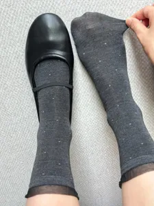 Detail view of dark grey women socks with white polka dots and elegant organza ruffle trim.
