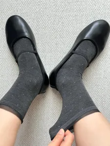 Close-up of sheer polka dot organza socks paired with black flat shoes, soft and breathable.