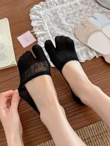 Close up view of black tabi split toe invisible socks, showing fine knit bow pattern details.